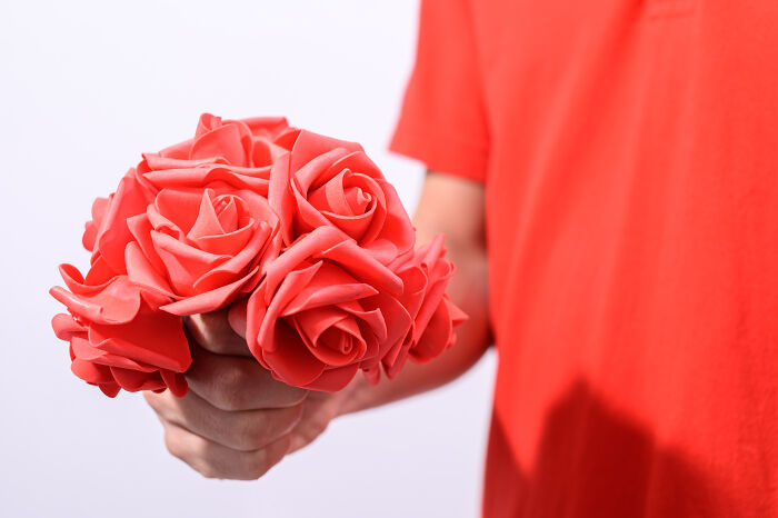 Person holding a bouquet of red roses, an adorable and simple Valentine's gift idea.