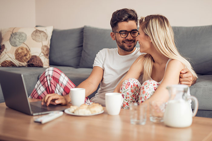 A couple in pajamas sharing a cozy moment on a sofa with coffee, illustrating lies men tell in relationships.