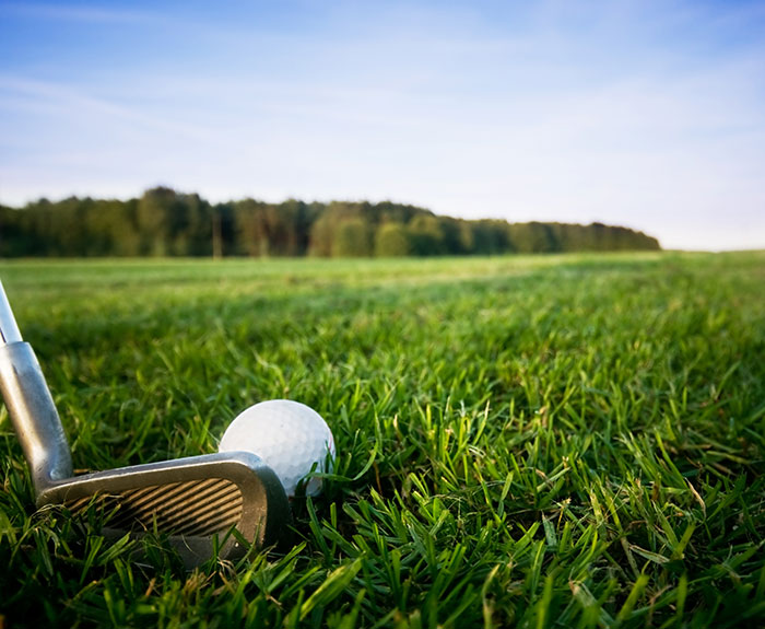 Golf club and ball on a grassy field, highlighting a lie men might tell about playing golf.