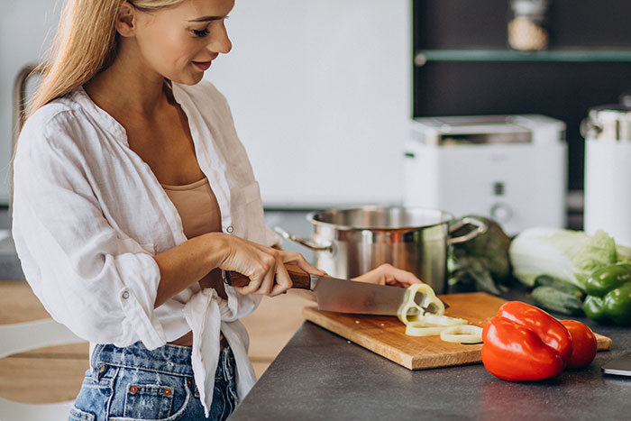 Woman chopping vegetables in a kitchen, illustrating the concept of lies men tell partners.