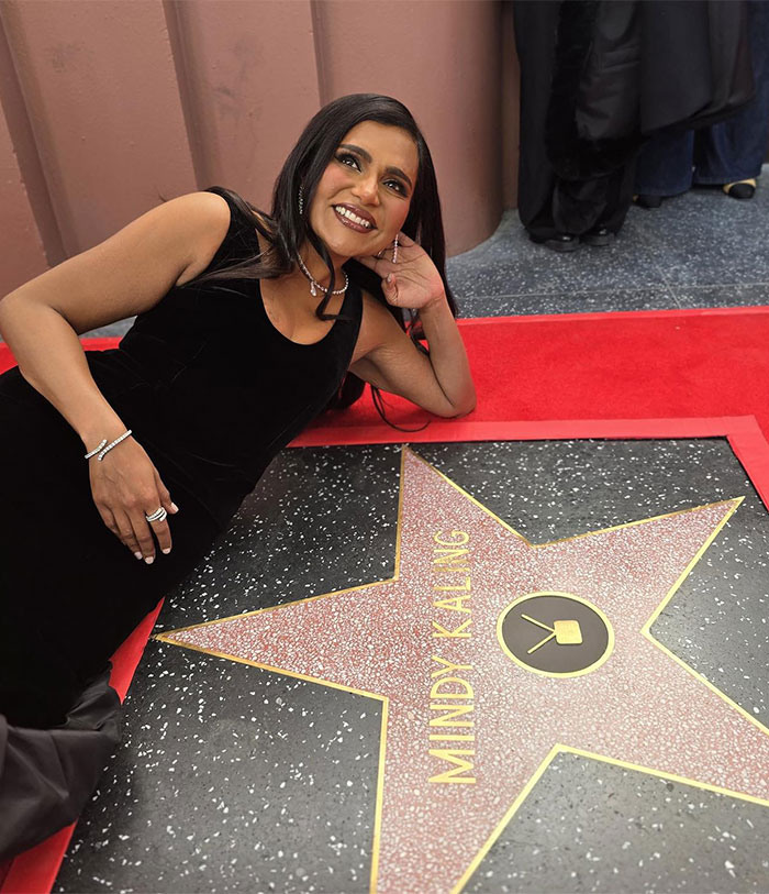 A woman in a black dress lies beside a Hollywood star on the Walk of Fame, smiling for the camera. A woman in a black dress lies beside a Hollywood star on the Walk of Fame, smiling for the camera.