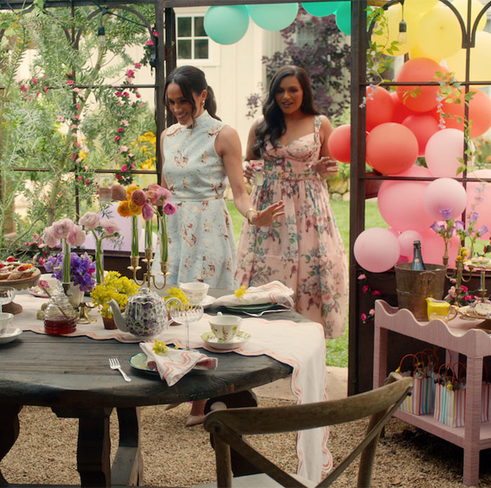 Two women in floral dresses decorate an outdoor table for a kids' party, colorful balloons in the background. Two women in floral dresses decorate an outdoor table for a kids' party, colorful balloons in the background.