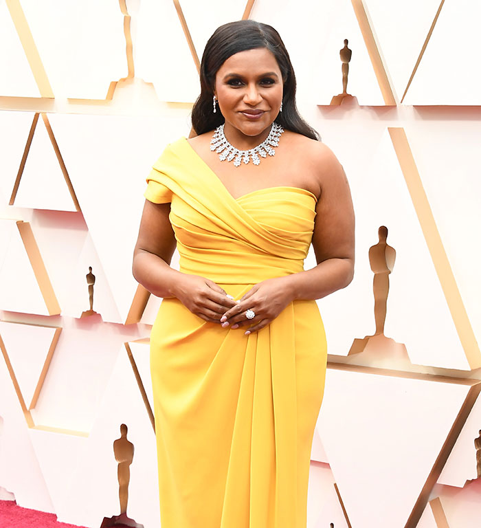 Mindy Kaling in a stunning yellow dress at a movie premiere, highlighting her slim figure.