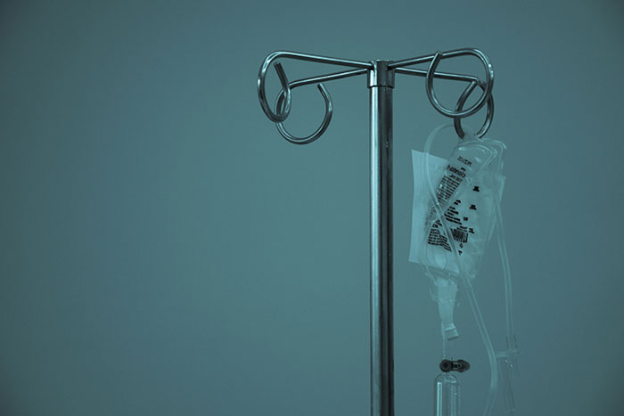 IV pole with an empty drip bag in a dimly lit hospital room, symbolizing life regrets of older people.