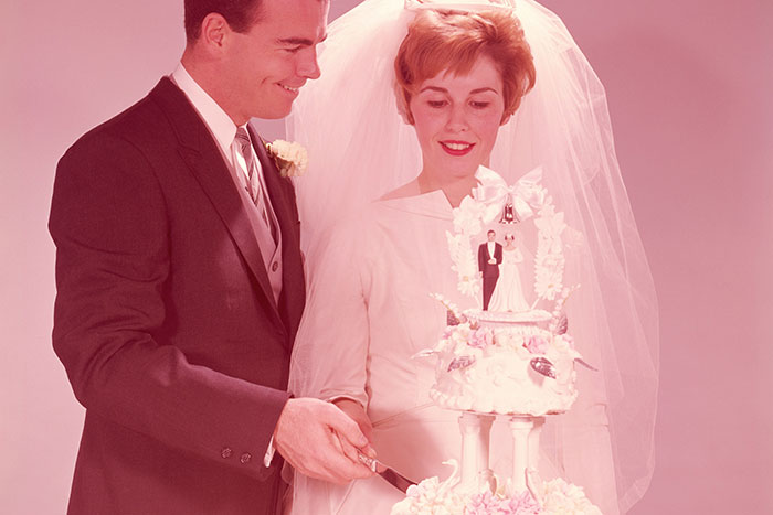 A bride and groom cutting a wedding cake, symbolizing life regrets shared by older people.