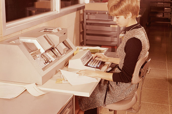 Woman working at a vintage computer in an office, symbolizing life regrets related to career choices of older people.