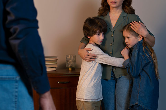 Woman comforting two scared children, representing life's biggest regrets and emotional moments.