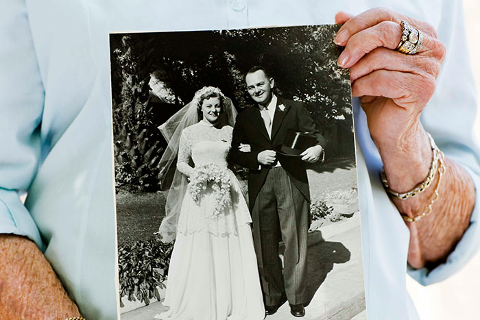 An older person holding a black and white wedding photo, symbolizing life regrets.