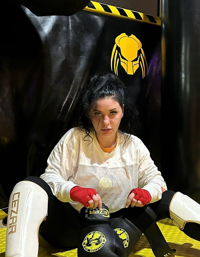 Woman in MMA gear, red gloves, preparing for controversial fight in gym setting. Woman in MMA gear, red gloves, preparing for controversial fight in gym setting.