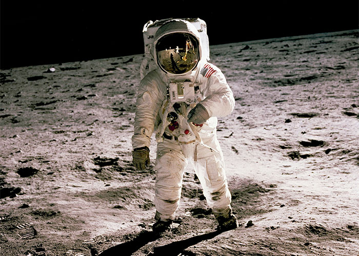 Astronaut walking on the moon in a spacesuit, reflecting the lunar surface, capturing an iconic moment.