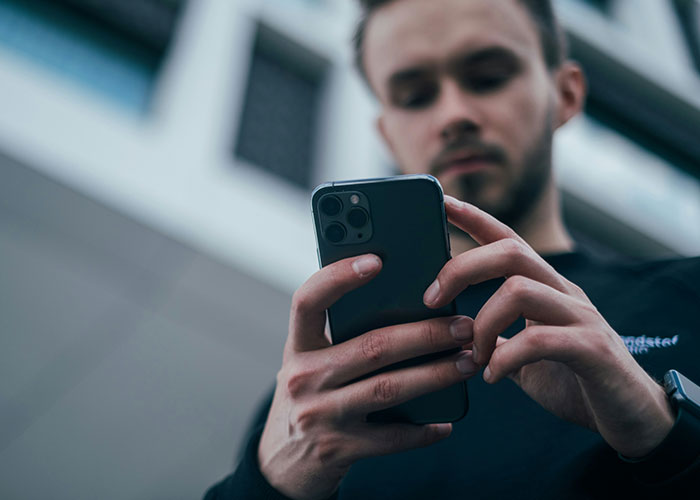 Person focused on smartphone, possibly capturing insane public conversations.