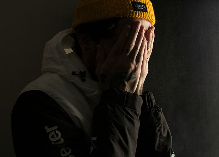 Person in a yellow beanie covers face, conveying shock, linked to insane things overheard in public.