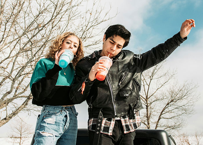 People enjoying drinks outdoors, embodying insane public moments with casual expressions and vibrant attire.