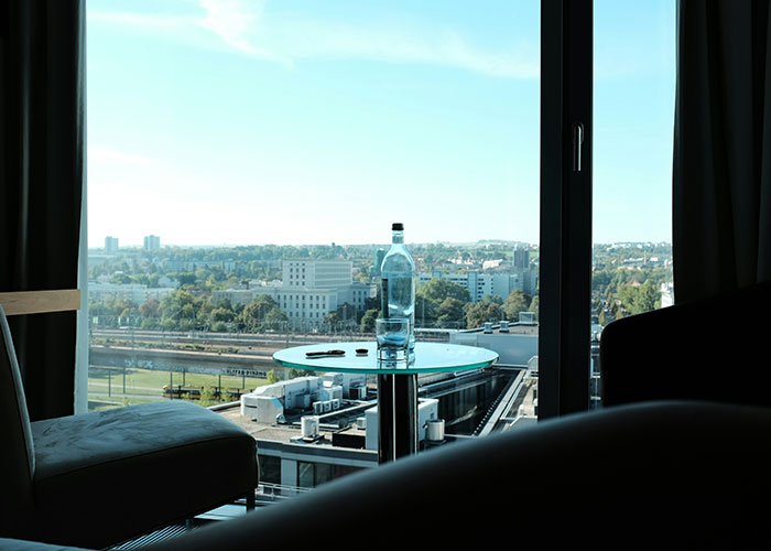 A bottle on a glass table in front of a city view, representing things overheard in public spaces.
