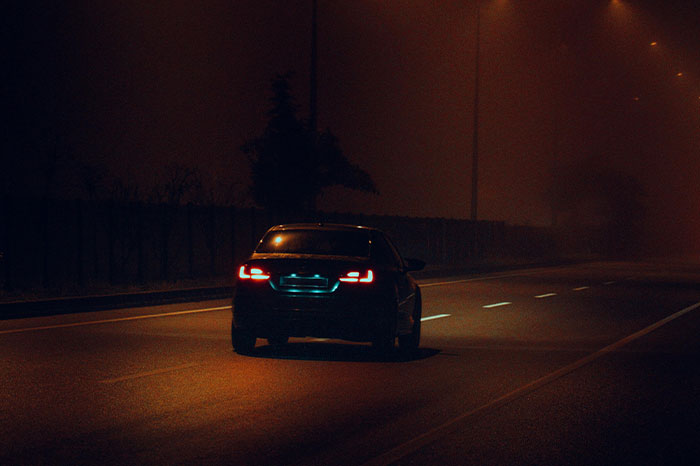 A car driving on an empty, dimly lit road at night, suggesting intuition spotting something wrong.