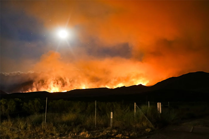 Wildfire blaze under moonlit sky, illustrating how intuition can spot danger early and prompt action to save lives.