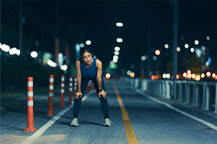 Runner paused on a dimly lit street, possibly sensing something wrong, illustrating the power of intuition.