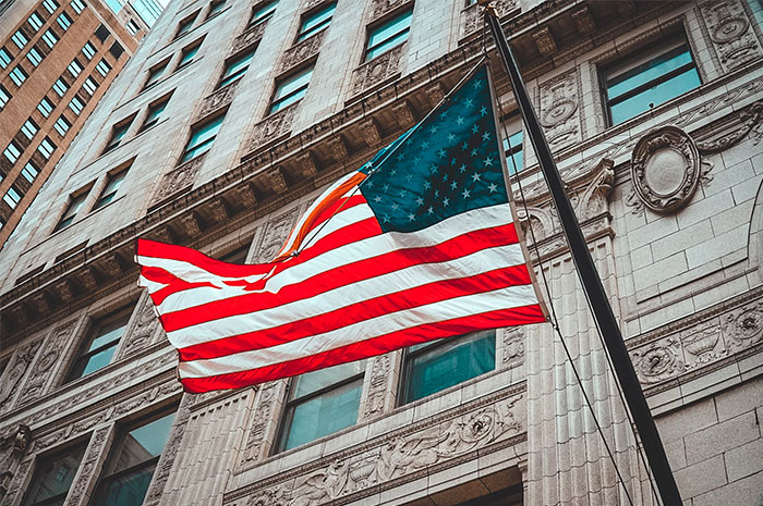 USA flag waving in front of a historic building, symbolizing intuition and vigilance.