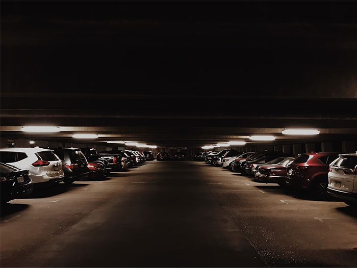 Dimly lit parking garage with parked cars, evoking a sense of intuition and caution.