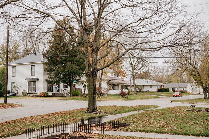 Quiet neighborhood street with houses and trees, capturing a serene autumn day.