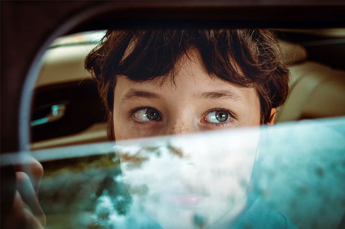 Child looking out a car window, appearing thoughtful; symbolizes intuition's role in sensing danger.