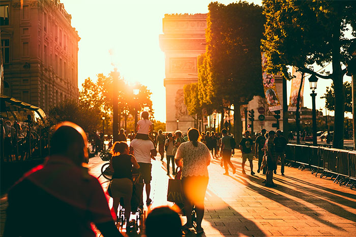 People walking on a sunlit street near the Arc de Triomphe, illustrating intuition and awareness in a bustling environment.