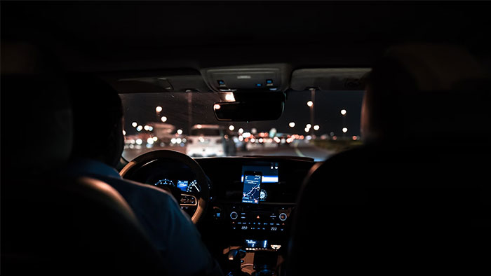 Driver at night, using GPS, highlighting the power of intuition to sense danger while navigating through city lights.