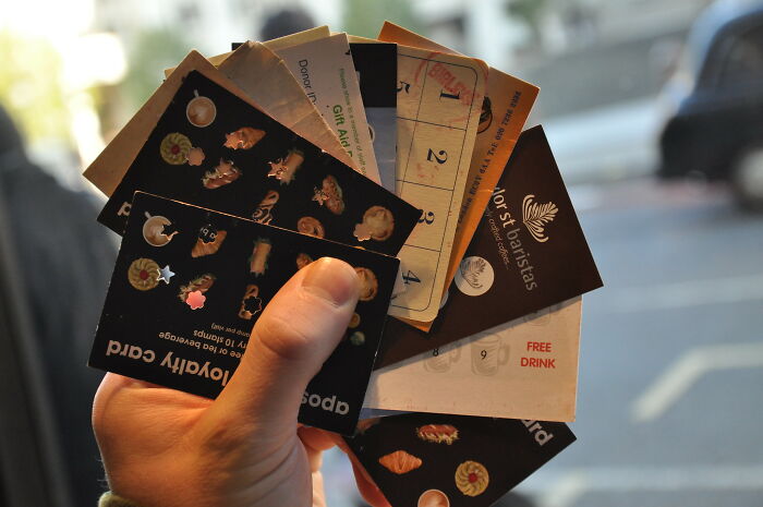 Hand holding various loyalty and gift cards, symbolizing sentimental items people carry despite being rather useless.