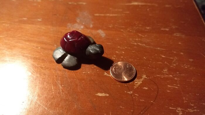Small turtle figurine beside a penny, carried for sentimental reasons despite being useless.