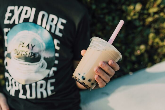 Person in a graphic T-shirt holding bubble tea, a sentimental yet rather useless item.