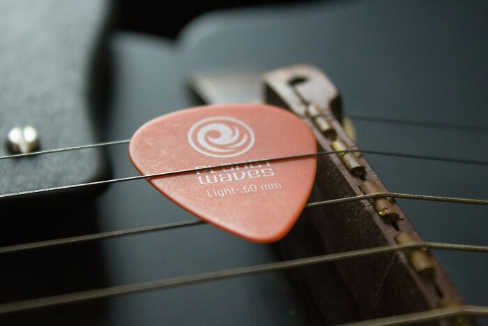 A guitar pick with sentimental value rests on guitar strings.