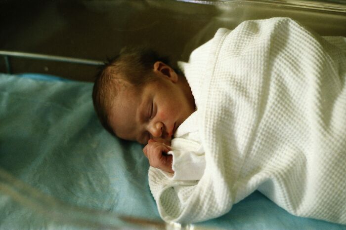 Newborn baby wrapped in a white blanket, peacefully sleeping in a hospital crib. Newborn baby wrapped in a white blanket, peacefully sleeping in a hospital crib.
