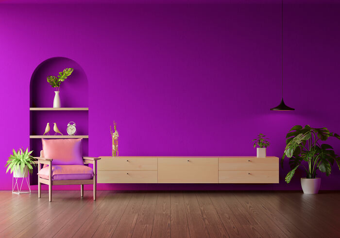Lounge redecorated with purple walls, a pink chair, and plants; showcasing a modern interior design style. Lounge redecorated with purple walls, a pink chair, and plants; showcasing a modern interior design style.