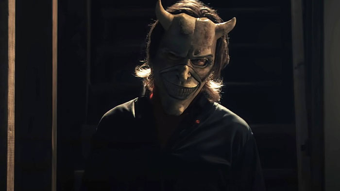A mysterious figure from "Black Phone 2" wearing a horned mask in a dark setting, hinting at anticipated movies of 2025.