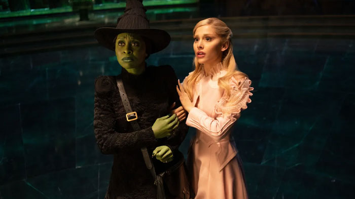 Two characters from "Wicked: For Good" in a dramatic scene, one with green skin and a black outfit, the other in a light pink dress, from anticipated movies 2025.
