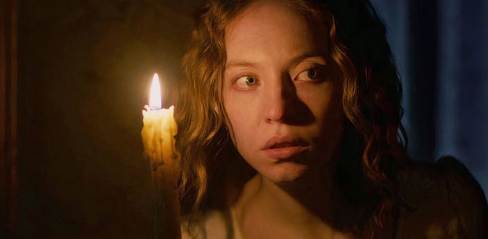 Woman from "The Housemaid" holding a candle in a dimly lit scene from an anticipated 2025 movie.