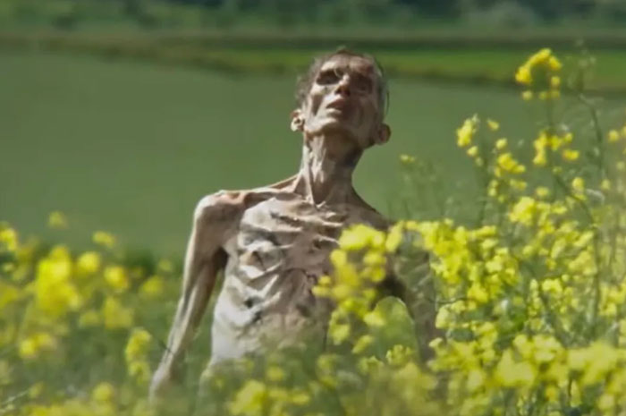 A skeleton-like figure from "28 Years Later" in a field of yellow flowers, related to anticipated movies coming out in 2025.