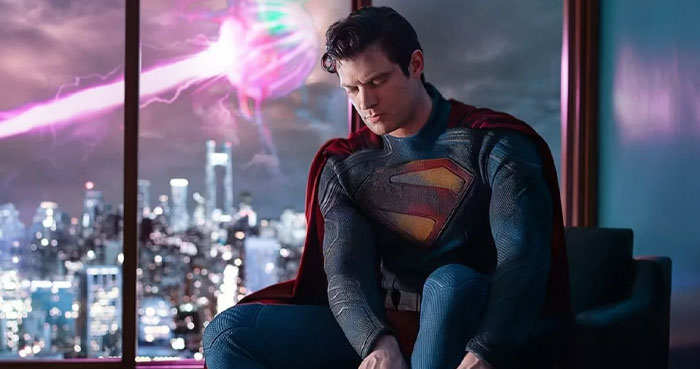 Superhero from "Superman: Legacy" in costume sitting by a window, skyline view, anticipated movie scene 2025.