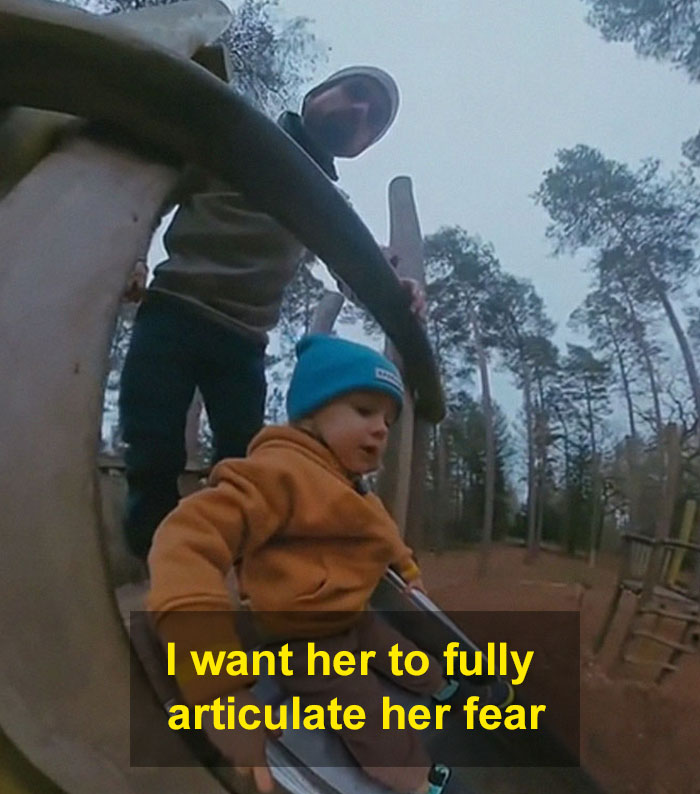 Toddler in orange jacket on slide with adult, illustrating negative reinforcement for overcoming fears.