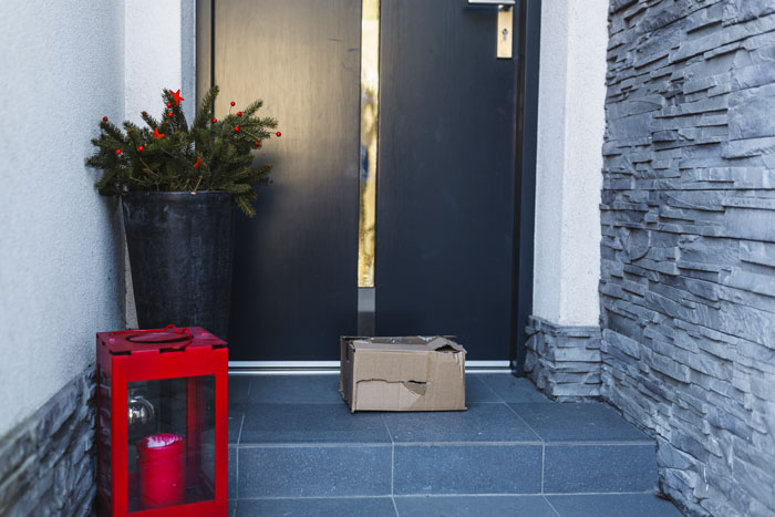 Package left on doorstep with a potted plant and red lantern, illustrating neighborhood delivery issue.