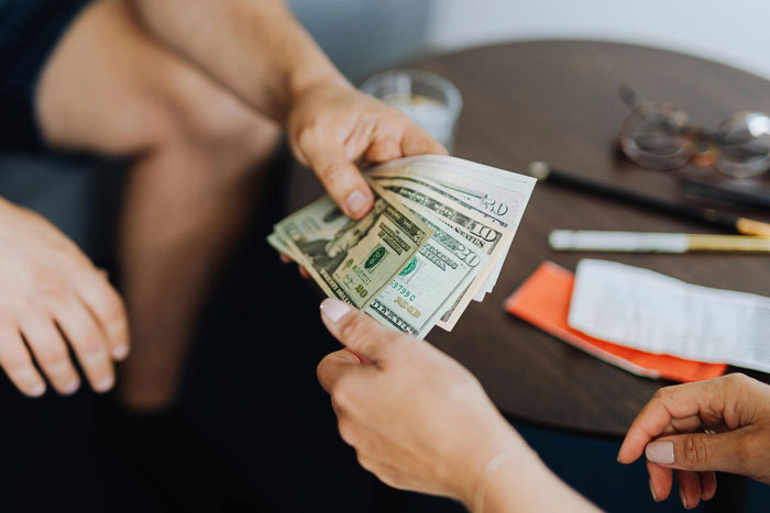 People exchanging cash at a table, representing ongoing requests from neighbor. People exchanging cash at a table, representing ongoing requests from neighbor.