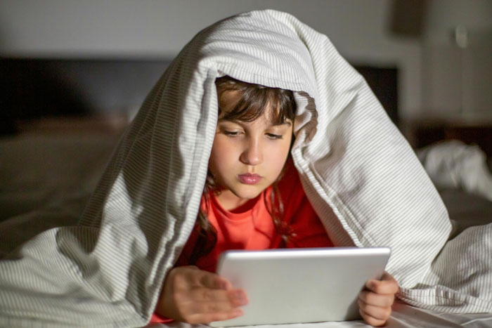 Child under blanket using tablet, highlighting neighbor won't change WiFi password issue.