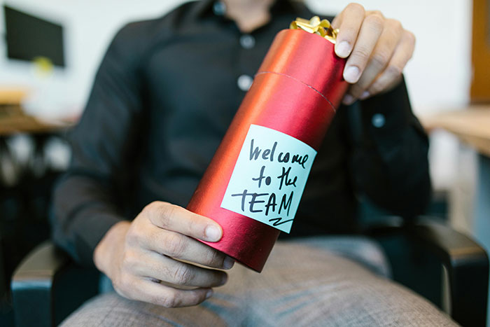 Man holding gift with "Welcome to the Team" note, symbolizing workplace dynamics and HR challenges. Man holding gift with "Welcome to the Team" note, symbolizing workplace dynamics and HR challenges.