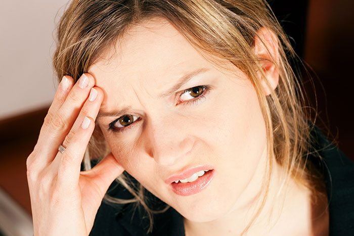 A concerned woman touching her forehead, illustrating tension in a conversation about bonding with stepchildren. A concerned woman touching her forehead, illustrating tension in a conversation about bonding with stepchildren.