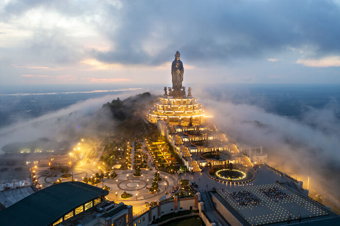 Aerial view of a colorful, illuminated statue and crowds of pilgrims, amidst clouds, capturing attention on Vietnamese social media. Aerial view of a colorful, illuminated statue and crowds of pilgrims, amidst clouds, capturing attention on Vietnamese social media.