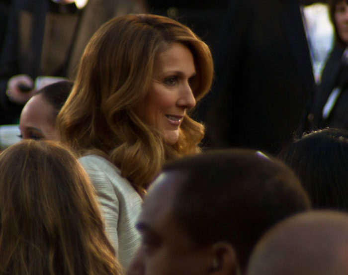 Person in a crowd at an event, smiling and interacting warmly in a social setting.