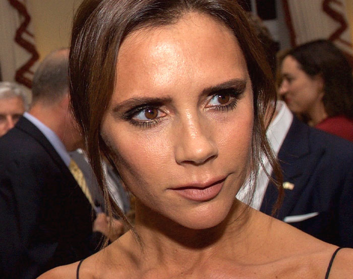 A woman with dark hair in an elegant setting, surrounded by people.