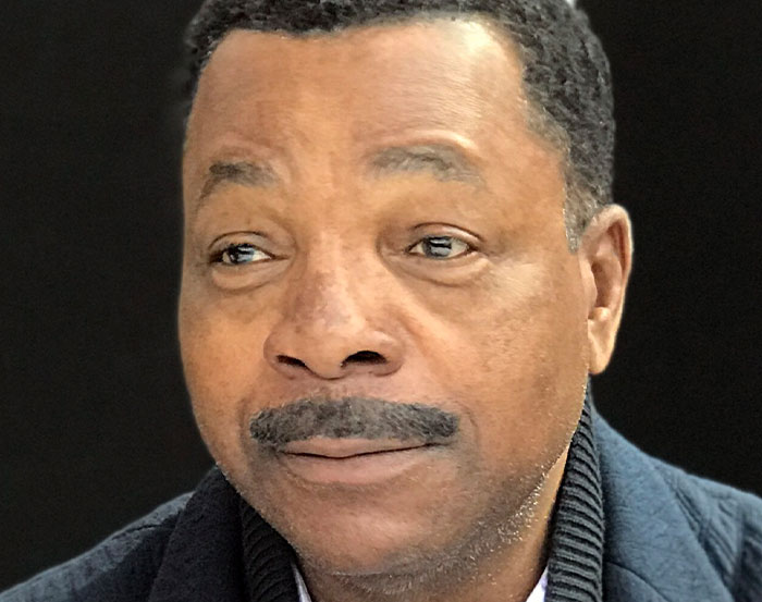 I don't know who this person is. A man with a mustache in a dark sweater, looking thoughtfully to the side.