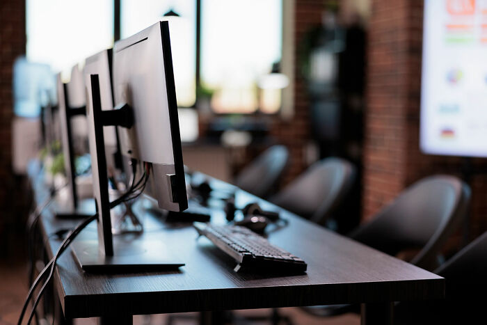 Modern office workspace with multiple computer monitors and keyboards, capturing an insane workplace moment atmosphere.