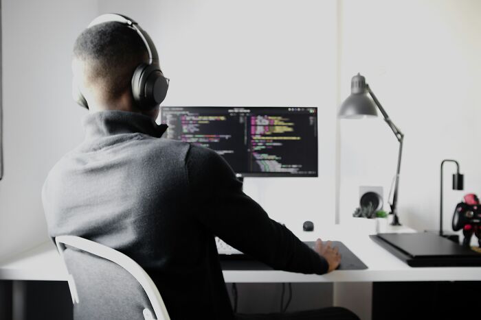 Person wearing headphones working on coding at a computer desk, in a minimalist office setup, exploring today I learned facts.